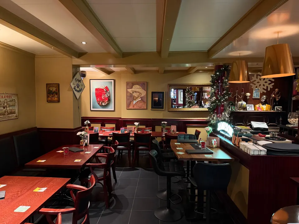 De zaal met schilderijen en houten tafels